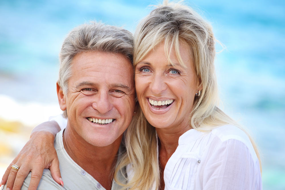 Smiling mature couple outdoors with beach in the background